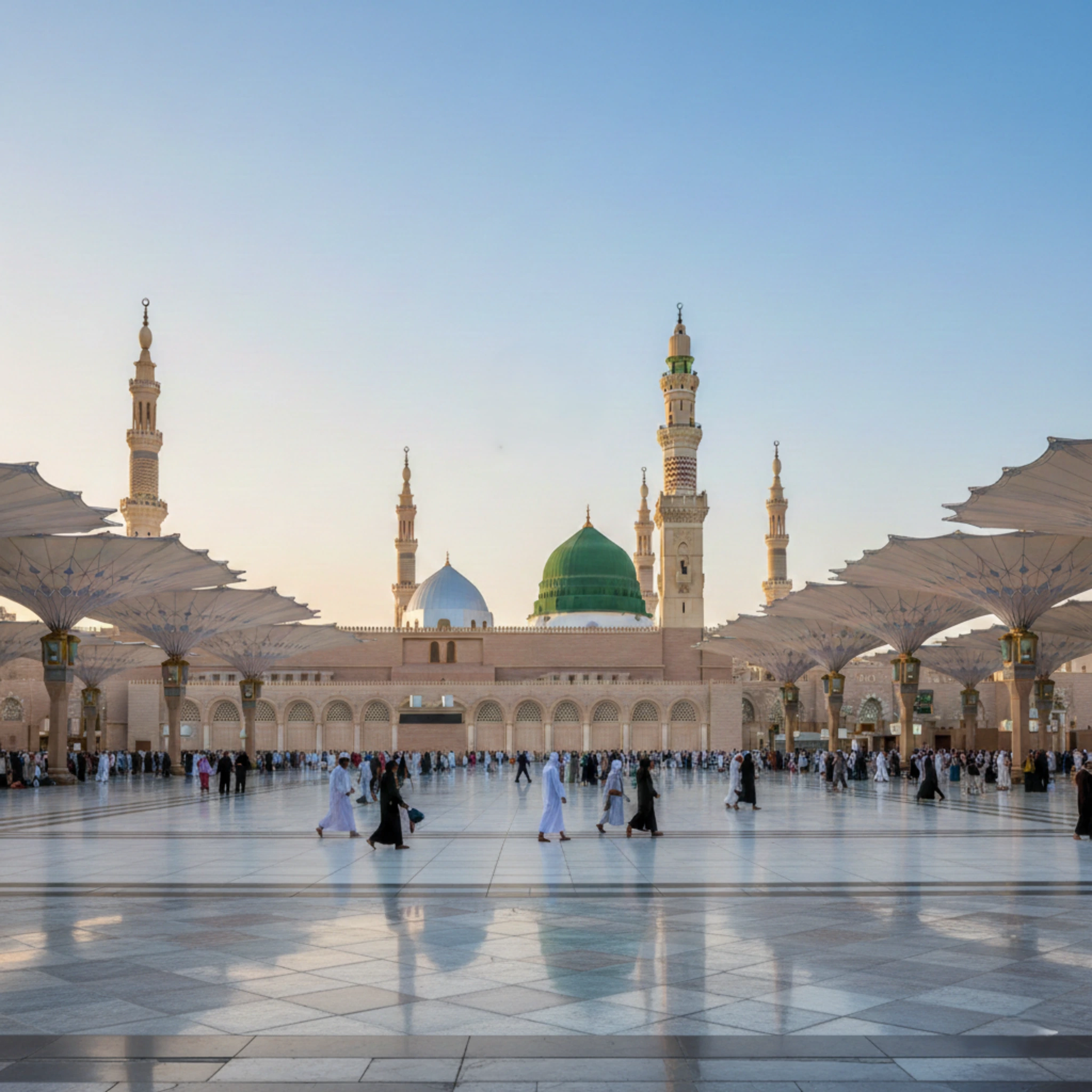 A large mosque courtyard with worshippers walking and a green dome under a clear blue sky